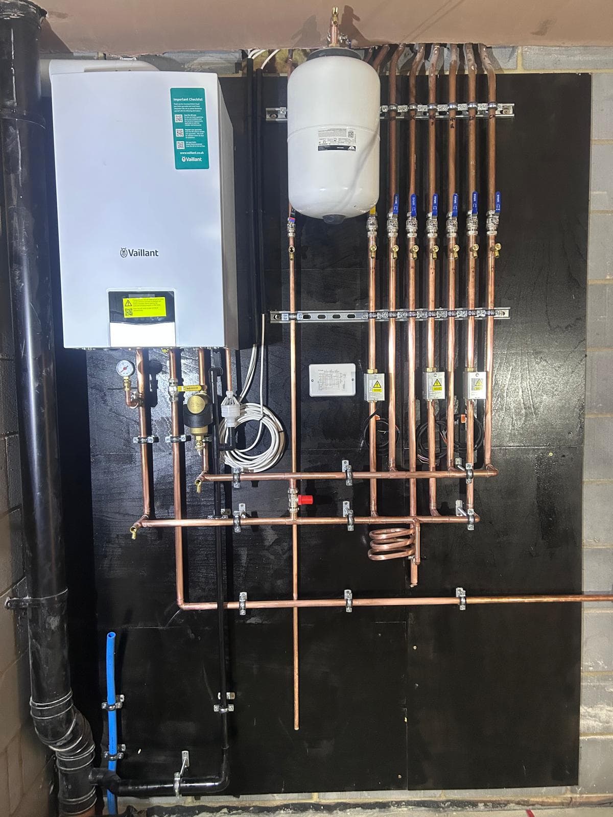 Wall-mounted Vaillant boiler with expansion vessel and parallel copper drops on a mounting board